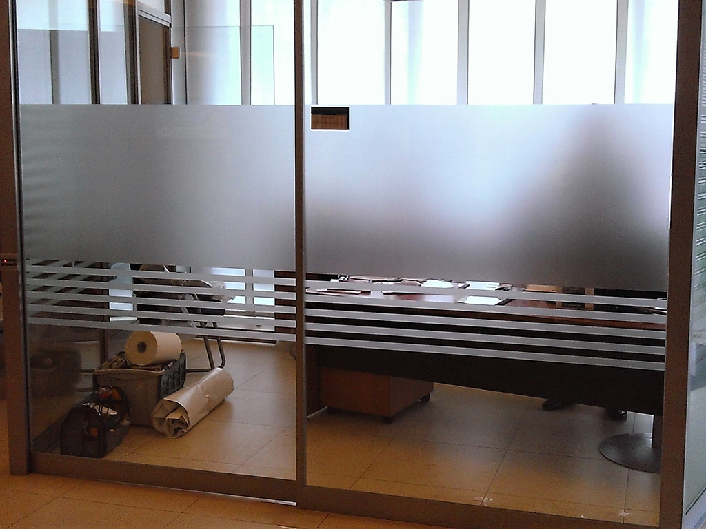 Vetrofanie effetto smeriglio con fasce prespaziate utili a creare privacy all'interno di uffici con pareti vetrate